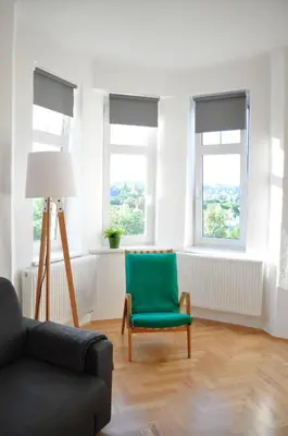 a living room with a green chair and windows at Central-Modern-Apartment in Prague