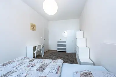 a white bedroom with a bed and a desk at Apartment Americká 8 in Prague