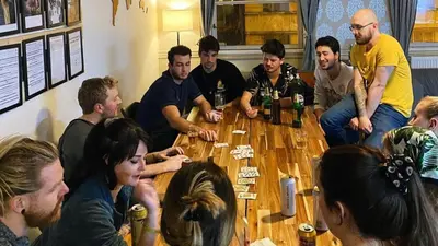 a group of people sitting around a table playing cards at Onefam Old Town in Prague