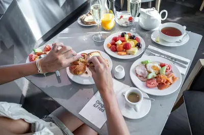 a person eating food at a table with plates of food at Dancing House - Tančící dům hotel in Prague