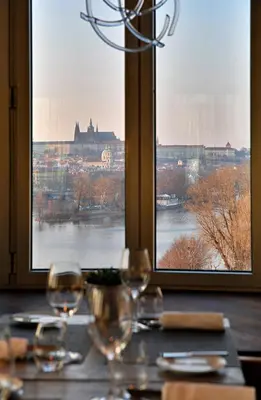 two wine glasses sitting on a table in front of two windows at Dancing House - Tančící dům hotel in Prague