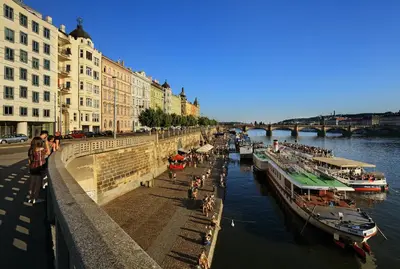 a group of boats docked in a river with buildings at Dancing House - Tančící dům hotel in Prague
