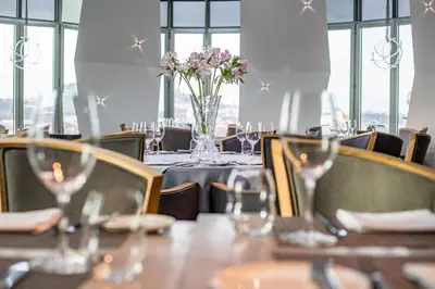 a table in a restaurant with a vase of flowers at Dancing House - Tančící dům hotel in Prague