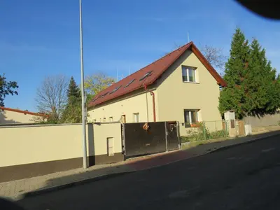 a white house with a red roof and a fence at Rivendell Apartments in Prague