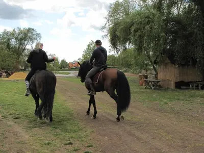 two people riding on horses on a dirt road at Rivendell Apartments in Prague