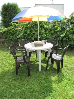 a table and chairs with an umbrella on the grass at Rivendell Apartments in Prague