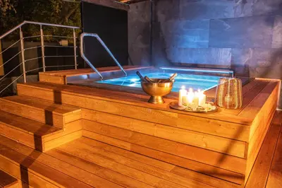a jacuzzi tub with candles on a wooden deck at Royal Apartmány in Dobříš