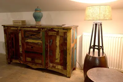 a wooden cabinet with a lamp and a vase on top at Bohemian Chic 2 Bedroom 2 Bathroom Loft with Hanging Chair in Prague