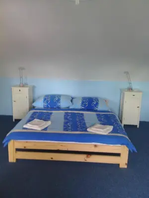 a bedroom with a bed with blue sheets and pillows at Penzion Paták in Kamýk nad Vltavou