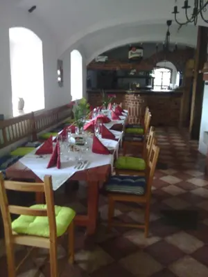 a dining room with a long table with red pillows at Penzion Paták in Kamýk nad Vltavou