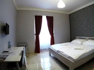 a bedroom with a bed and a desk and a window at Penzion U tri statkaru in Dobříš