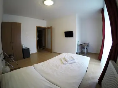 a bedroom with a white bed and a television at Penzion U tri statkaru in Dobříš