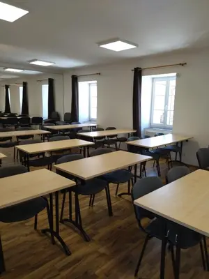 an empty classroom with rows of tables and chairs at Penzion U tri statkaru in Dobříš