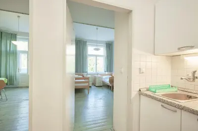 a kitchen with a sink and a living room at Hostel Mikoláše Alše in Prague