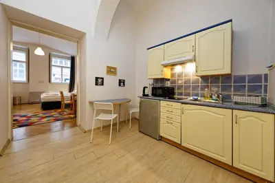 a kitchen with white cabinets and a table in a room at Apartments Truhlarska 31 in Prague
