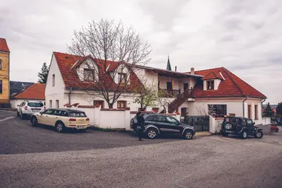 a white house with cars parked in front of it at Apartmány Malý mnich in Mníšek pod Brdy