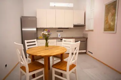 a kitchen with a wooden table with chairs and a refrigerator at Art Nouveau Apartment in Prague