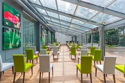 a room with green and white chairs and windows at Holiday Inn Prague by IHG in Prague