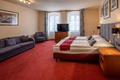 a bedroom with a large bed and a couch at Pension U Lilie in Prague