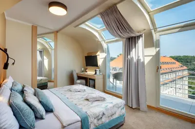 a bedroom with a bed and a large window at Hotel Clement in Prague