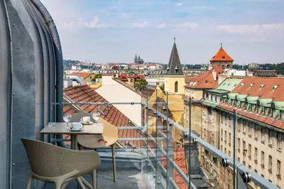 a balcony with a table and chairs looking out at a city at Hotel Clement in Prague