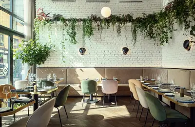 a restaurant with tables and chairs and plants at Hotel KINGS COURT in Prague