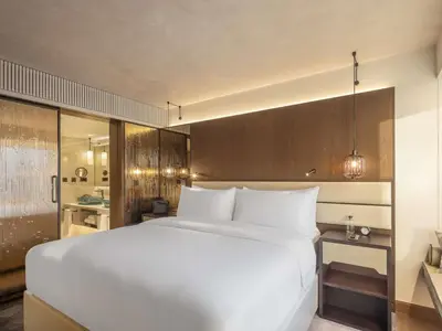 a bedroom with a large white bed and a bathroom at Fairmont Golden Prague in Prague