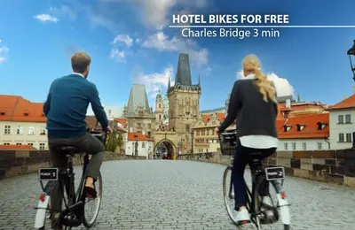 two people riding bikes in front of a city at Metropolitan Old Town Hotel - Czech Leading Hotels in Prague