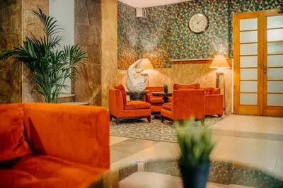 a living room with orange furniture and a clock on the wall at Metropolitan Old Town Hotel - Czech Leading Hotels in Prague