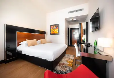 a bedroom with a large bed and a red chair at Grand Majestic Hotel Prague in Prague
