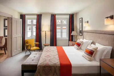 a hotel room with a bed and a chair at Augustine, a Luxury Collection Hotel, Prague in Prague