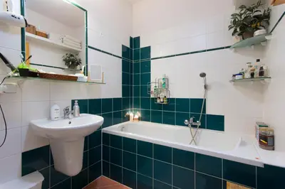 a green and white bathroom with a sink and a tub at Victoria Design Stays - Apartment Rehorova in Prague