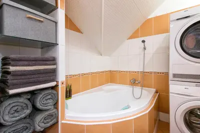 a bathroom with a tub and a washing machine at Apartment Neratovice in Neratovice