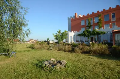 a building and a yard with a rock in the grass at Penzion Folbr in Dlouhá Lhota