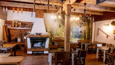 a restaurant with a fireplace and wooden tables and chairs at Penzion Pod Houskou in Blatce