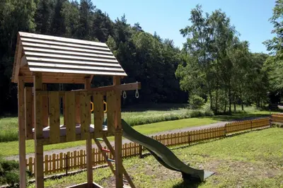 a wooden playground with a slide in a park at Penzion Pod Houskou in Blatce
