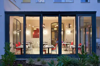 a restaurant with glass doors and tables and chairs at Red & Blue Design Hotel Prague in Prague