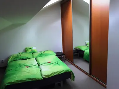 a bedroom with a green bed and a mirror at Sunny Two-story Apartment Kyje in Prague