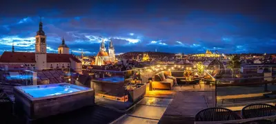 a rooftop terrace with a hot tub and a city at night at Billionaires Boutique Residence & Premium Suites, Old Town in Prague