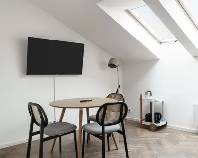 a dining room with a table and chairs and a tv at Limehome Prague Halkova in Prague