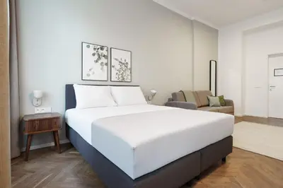 a bedroom with a large white bed and a couch at Limehome Prague Halkova in Prague
