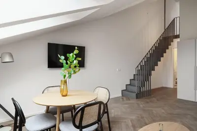 a dining room with a table and chairs and a staircase at Limehome Prague Halkova in Prague
