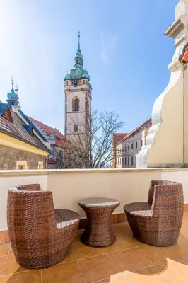 a balcony with chairs and a clock tower at Hotel U Rytíře in Mělník