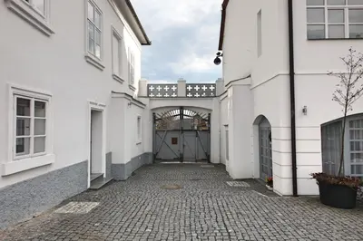 an alleyway between two white buildings with a gate at St. Terezie - Baroque Residence in Prague