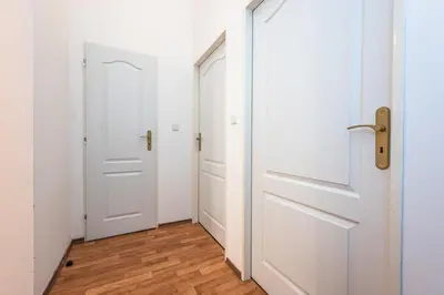 an empty hallway with white doors and wood floors at Apartment Lublanska 48 in Prague