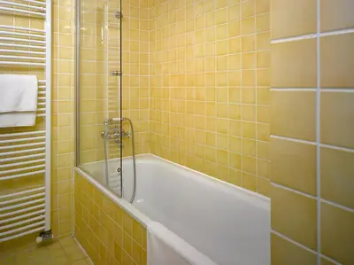 a yellow tiled bathroom with a tub and a shower at Hotel La Romantica in Mladá Boleslav