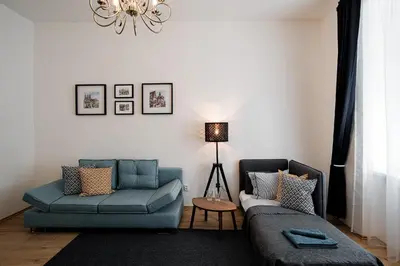 a living room with two blue couches and a table at Apartment Gesse Březinova in Prague
