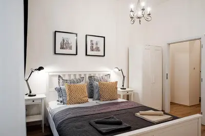 a white bedroom with a large bed with pillows at Apartment Gesse Březinova in Prague