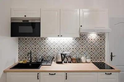 a kitchen with white cabinets and a stove top oven at Apartment Gesse Březinova in Prague