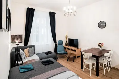 a bedroom with a bed and a table and a desk at Apartment Gesse Březinova in Prague